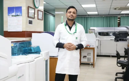 Indrajit Sarkar, Senior Laboratory Scientist and Public Health Researcher, standing with a Cobas e 601 analyzer in a high-volume diagnostic center in Dhaka.